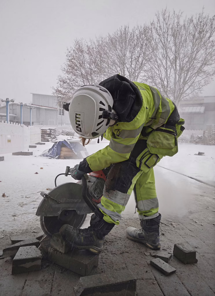 Entti Oy:n viherrakentaja sahaa kiviä talvisessa säässä